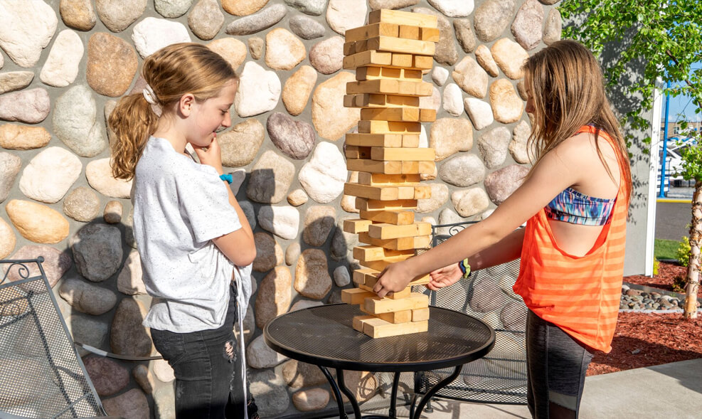Two kids playing with the jumbo jenga blocks on a sunny day