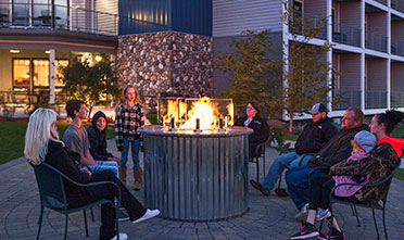 a group of people sitting in chairs facing the fire table in front of Park Point Marina Inn