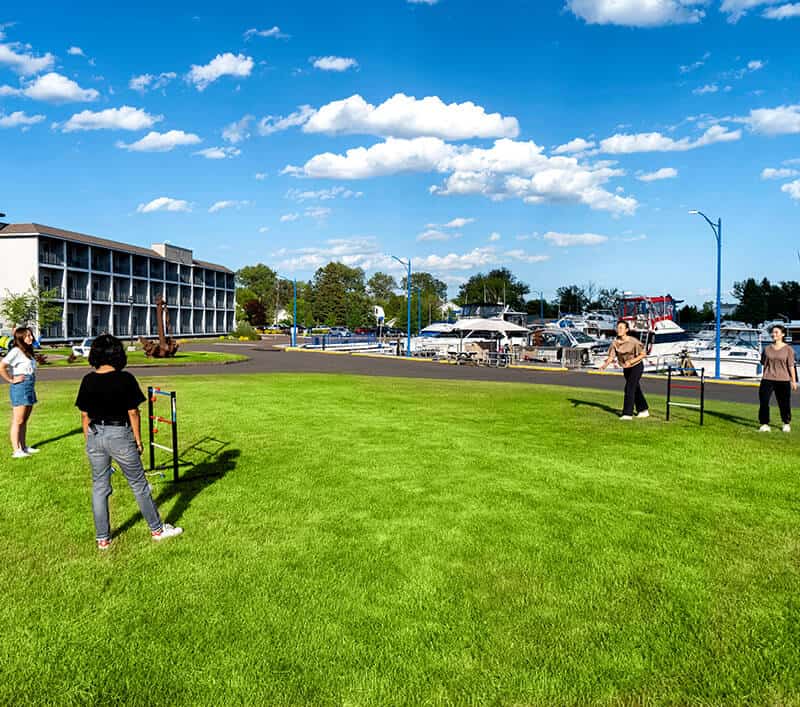 four teenagers having fun on the grass outside of Park Point Marina Inn