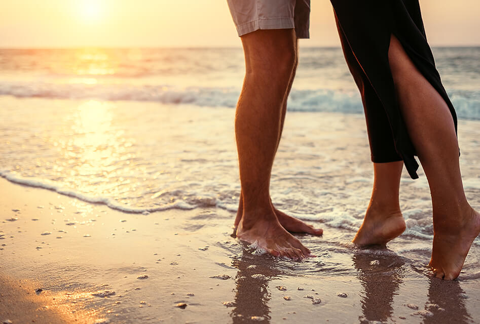 a couple walking along the beach during sunset