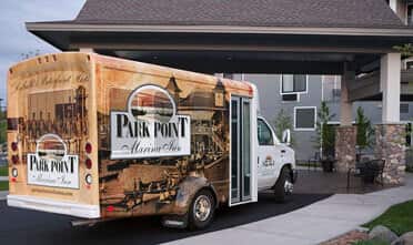 a shuttle with Park Point Marina Inn's logo sits in front of the entrance, waiting for guests to board