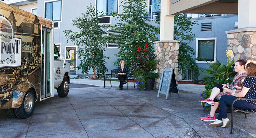 Smiling ladies sitting on the bench next to Park Point Marina Inn's entrance waiting to board the shuttle