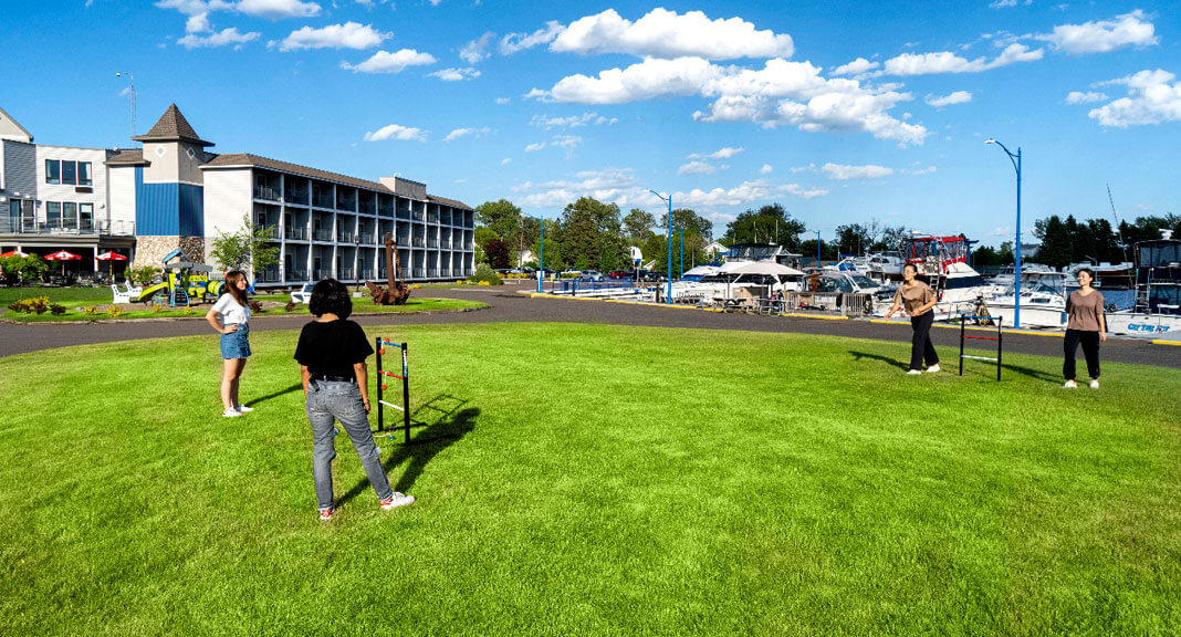 four teenagers having fun on the grass outside of Park Point Marina Inn