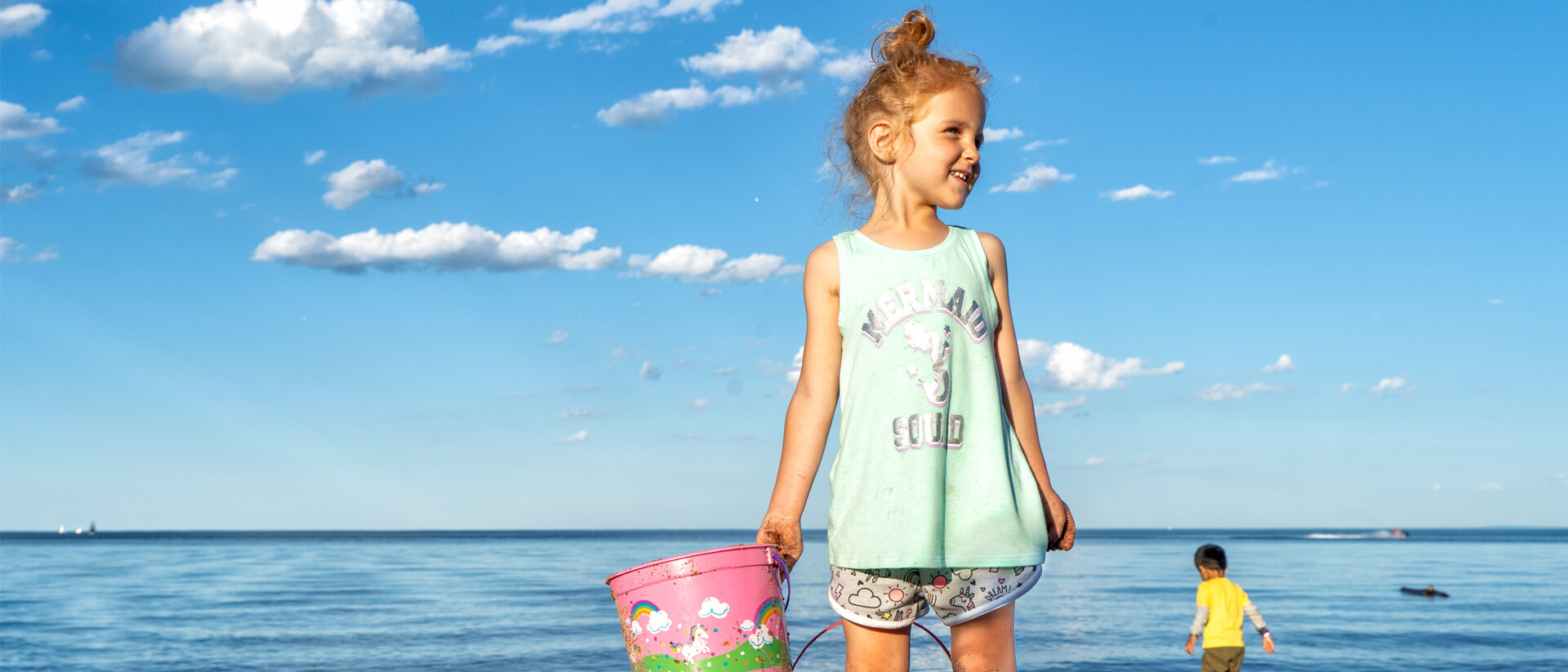 A girl holds a bukcet on the beach